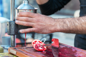 Man making pomegranate juice by hand with hand press juice maker. Street Food in Turkey.