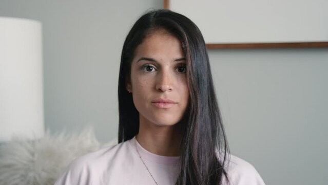 Pretty brunette hispanic woman looks up to camera with stoic, serious expression