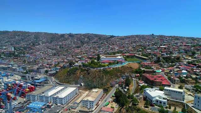 Aerial Forward Shot Of Residential Houses In Town On Hills By Commercial Dock - Valparaiso, Chile