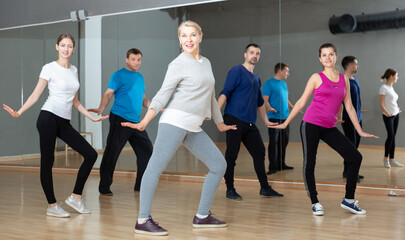 Fototapeta na wymiar Group of happy adult people enjoying active social dances in modern dance studio