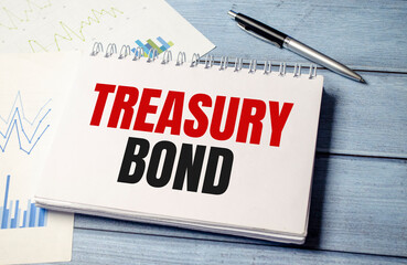 Notepad with text TREASURy BOND, on business charts and pen and charts