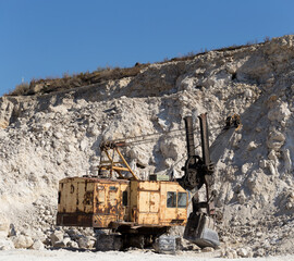 Fototapeta premium Yellow excavator - digging machine for digging and dumping the soil. Work in the quarry.