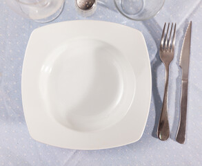 Empty plate and serving pieces on table, nothing served.