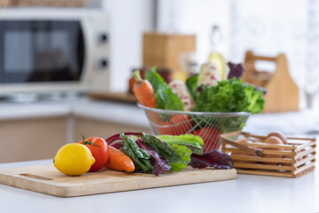 Fresh fruit and vegetables, including fresh salad, fresh tomatoes, carrots, fresh corn, eggs, Swiss chard, lemon on the kitchen counter for cooking.