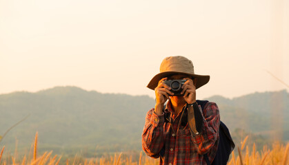 Asian man holding a camera with both hands.man wearing a hat taking pictures,copy space