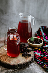 Agua de Jamaica or roselle mocktail drink, summer beverage in mexico with ice and dry hibiscus petals on table background