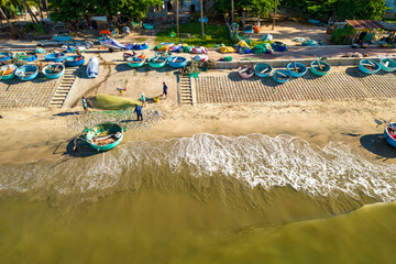 A coastal fishing village seen from above on a summer morning as fishermen remove their nets and sell them to feed their families peacefully in Mui Ne, Vietnam