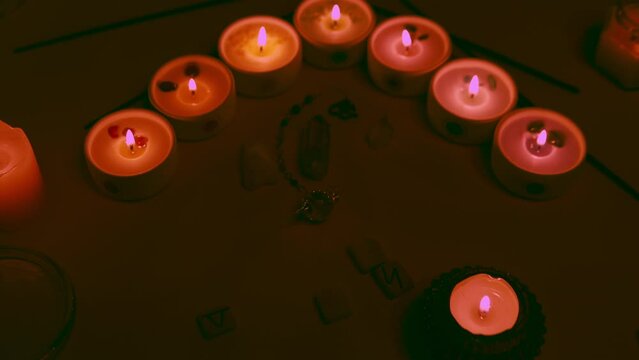 Mystic esoteric ceremony with candles, crystals, runes and quartz pendulum.