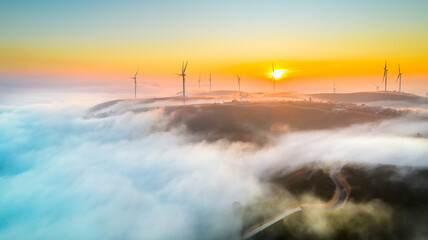 Aerial view top hill at dawn with fog covering small village in valley, beautiful wind power poles...
