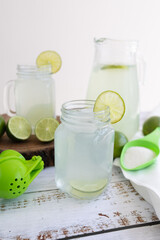 Jar glass of lemonade drink with green lemons or lime on a white background in Latin America