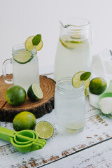 Jar glass of lemonade drink with green lemons or lime on a white background in Latin America