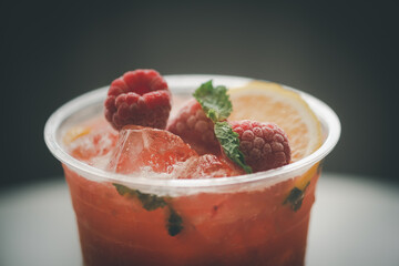 Cold sparkling tea with lemon slice, berry, mint and ice in a glass