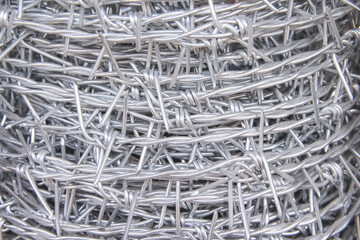 Close up barbed steel wire roll abstract white grey background