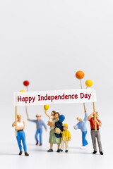 Miniature people holding flags with word Happy Independence day on grey background