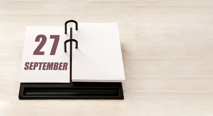 september 27. 27th day of month, calendar date. Stand for desktop calendar on beige wooden background. Concept of day of year, time planner, autumn month