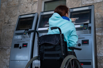 A Caucasian woman in a wheelchair does not reach the self-service checkout at the railway station....