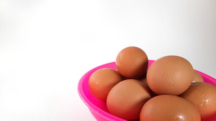 Details of domestic chicken eggs in a pink bowl on a white background