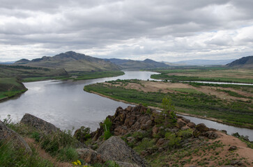 The valley of the river under an overcast cloudy sky. View of the river from a height.