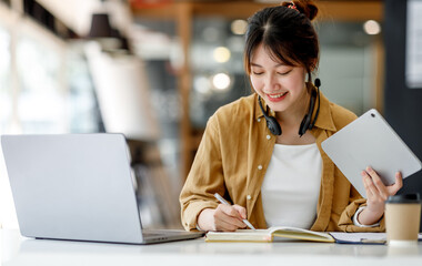 Young adult happy smiling Hispanic Asian student wearing headphones talking on online chat meeting using laptop in university campus or at virtual office. College female student learning remotely.