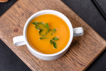 Delicious fresh pumpkin puree soup decorated with parsley in a white plate