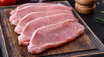 Raw fresh pork meat sliced on a wooden cutting board