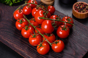 Fresh cherry tomatoes on a black background with spices