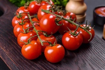 Fresh cherry tomatoes on a black background with spices