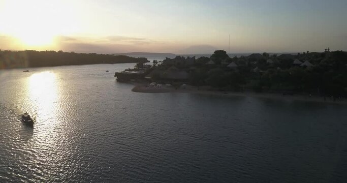 Plataran l'Harmonie Bay, Bali, Indonesia. Aerial drone view. Flight toward the coastline at sunset, Java island and Raung volcano on the horizon.