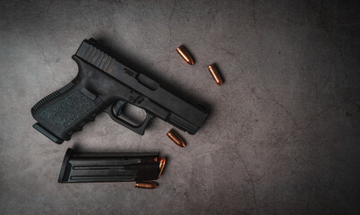 black 9mm pistol on an old concrete floor with 9mm ammunition next to it. top view