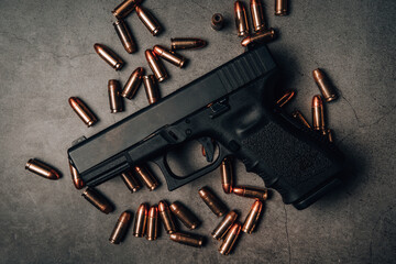 black 9mm pistol on an old concrete floor with 9mm ammunition next to it. top view