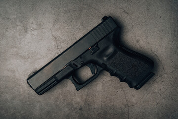 black 9mm pistol on an old concrete floor. top view.
