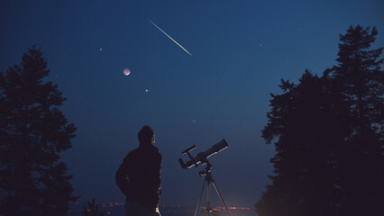 Silhouette of a man, telescope, stars, planets and shooting star under the night sky. © astrosystem