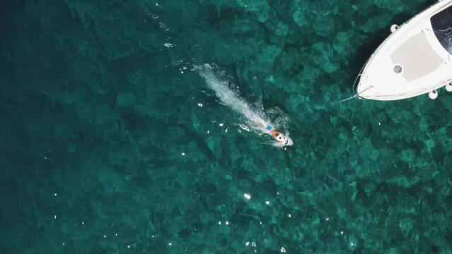 An aerial drone shot of someone using a seascooter. Enjoying the freedom of the ocean, next to a boat.