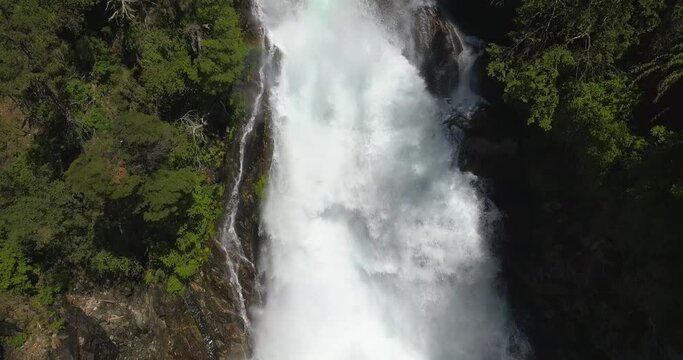 Drone image panning over a waterfall where you can see from the base to where the waterfall is born.