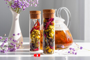 Tea with flowers in a glass tea jar. Glass teapot with brewed drink. Advertising tea company,...