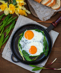 Fried eggs with fried green wild garlic. Breakfast with fresh wild garlic. Spring seasonal products concept