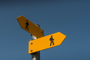 Two yellow signposts with walking figures and arrows point in different directions, Canton Thurgau, Switzerland