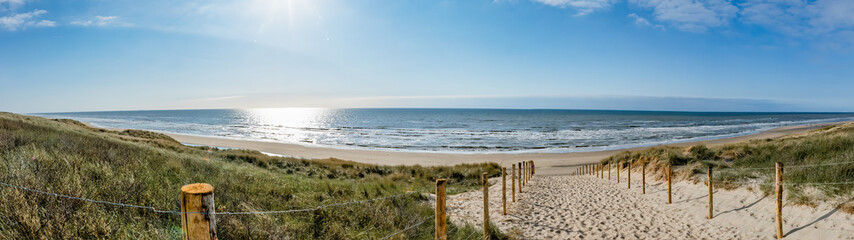 Un chemin avec de nombreuses pistes, délimité par des poteaux en bois sur la dune de sable avec de l& 39 herbe sauvage et de la plage à Noordwijk sur la mer du Nord en Hollande Pays-Bas - Paysage marin panoramique avec ciel bleu et nuages