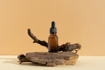 Bottle of dark amber glass with hyaluronic acid or face serum near dry branch on a beige background. Concept natural cosmetics with organic components. Copy space for your design. Front view