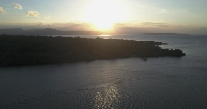 Plataran l'Harmonie Bay, Bali, Indonesia. Aerial drone view. Flight toward the coastline at sunset, Java island and Raung volcano on the horizon.