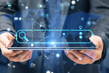 Close up of businessman hand holding pad with creative search bar and digital blue map icons on...