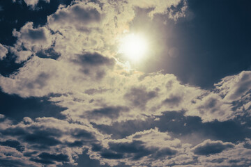 Fototapeta na wymiar The sun peeks out from behind cumulus clouds. Anxious mood.