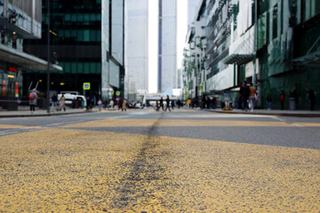 Defocused view to skyscrapers of business center, road marking in a city. People on a street on high rise buildings background