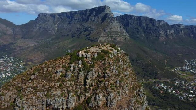 Drone shot of Lions Head in Cape Town - drone is reversing from the top of Lions Head, facing Table Mountain. Snippet could ideally be used for travel related videos or Cape Town movies.