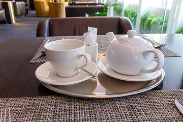 Teapot and cup and saucer on the table in restaurant