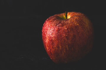 Red delicious apple with water drops, dark moody photo. Abstract fruit background