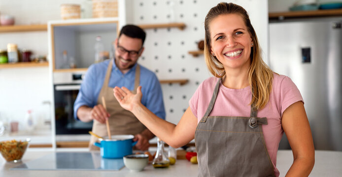 Young happy couple is enjoying and preparing healthy meal in their kitchen together