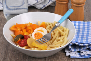 Salade composée avec des macaronis et des légumes servie dans un saladier avec une fourchette