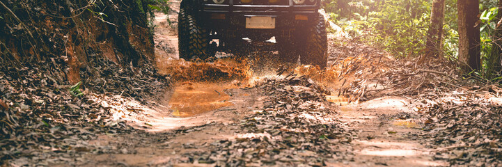 front view of the off-road vehicle Driving through a mud hole, in a forest, on a muddy road © PIPAT