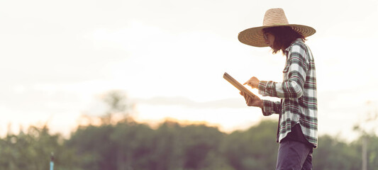 An Asian male farmer is using a tablet to store plant data in his farm. organic agriculture concept use of agricultural technology